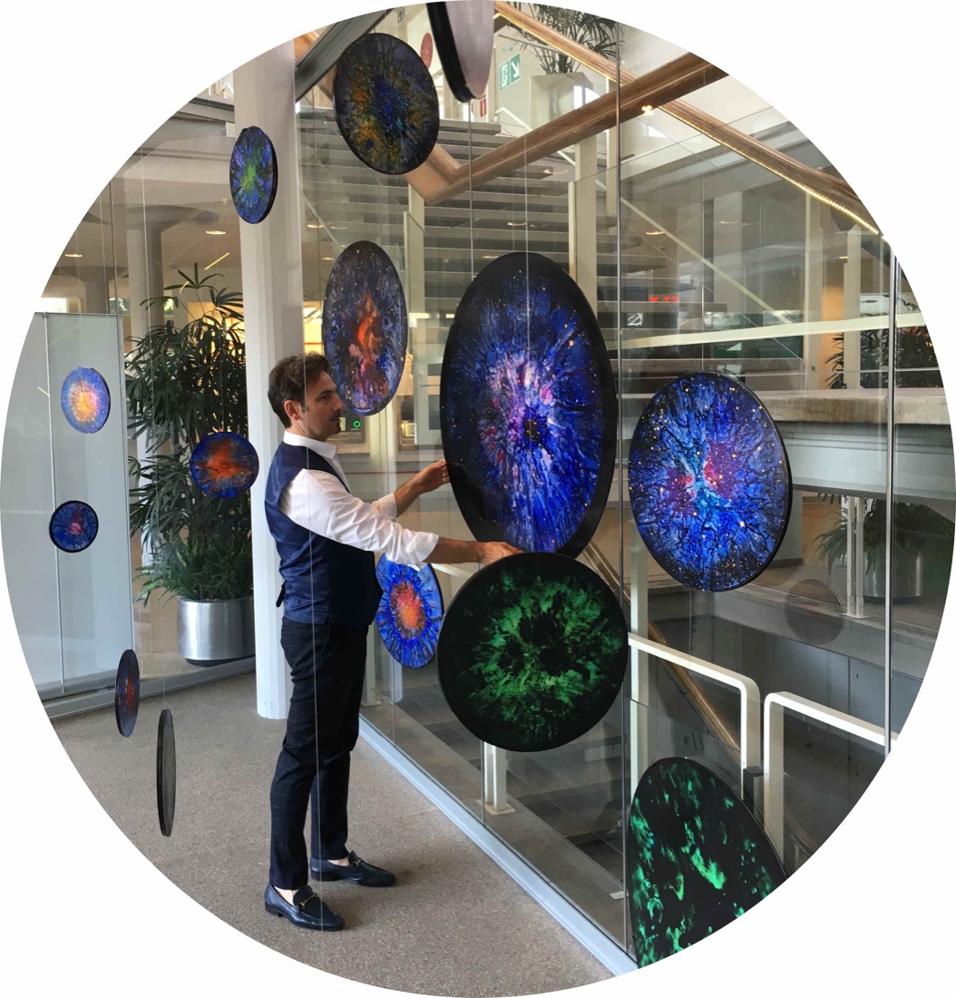 Enrico Magnani hanging round Supernova paintings on a glass wall at CERN