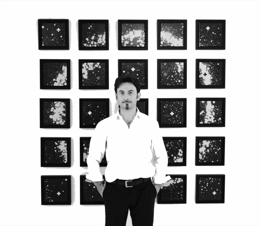 Enrico Magnani, portrait in front of a wall of small square works